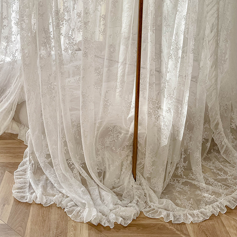 White floral lace ruffle canopy curtains draped over wooden floor around 4-poster bed