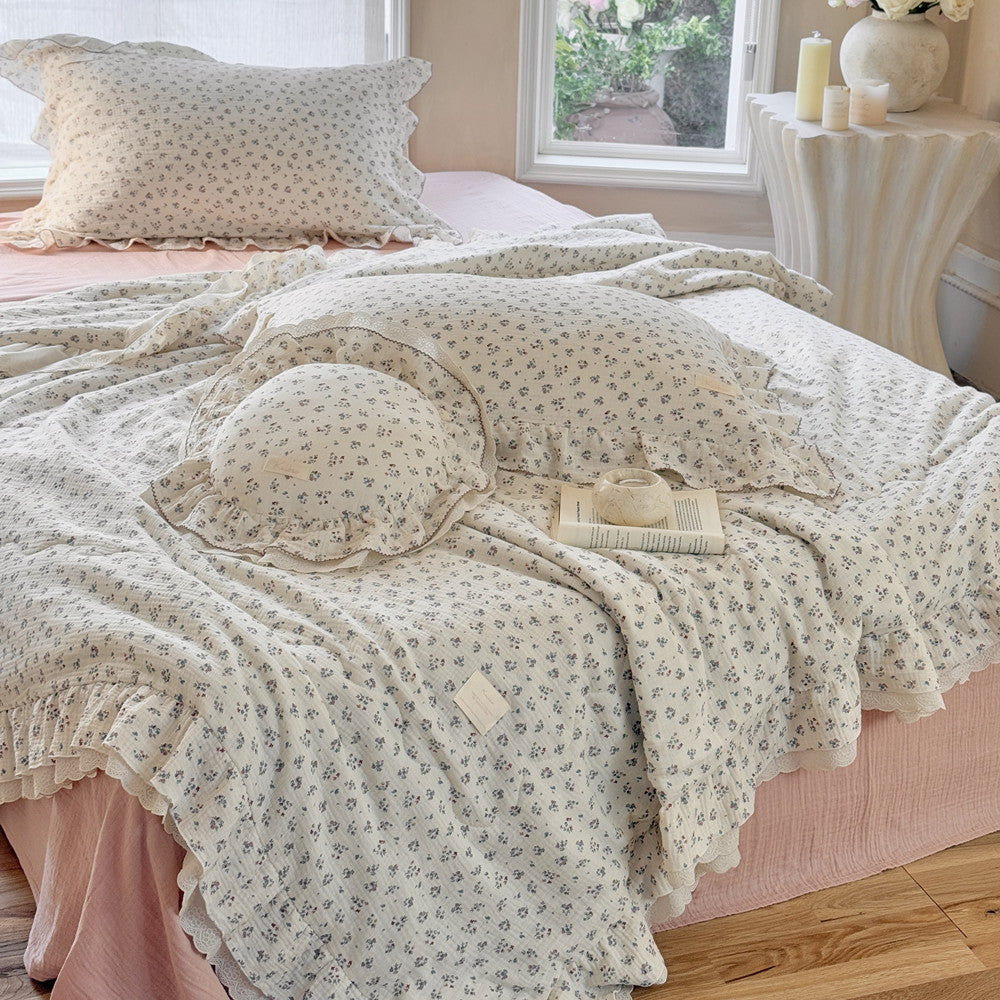 Romantic cotton comforter with ditsy floral print and ruffled lace, styled in a serene bedroom