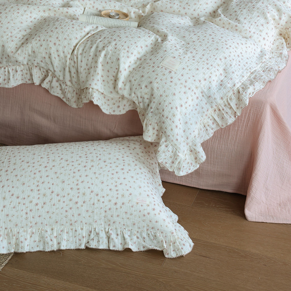 Close-up of floral twin duvet cover and pillow shams with ruffled trim, showing a pink bed sheet