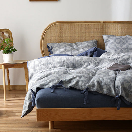 ALuxury Jacquard Cotton Bedding Set in navy blue on a Queen size bed with navy sheet and rattan headboard.