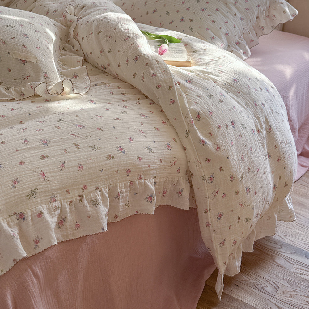 Ruffled pink floral muslin duvet cover set styled in a cute girl's room with matching pillows and flat sheet