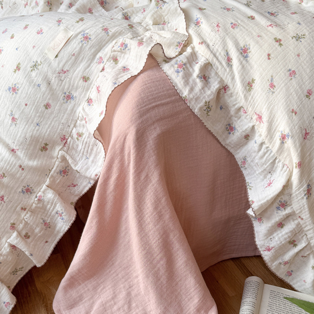 Close-up of pink floral cotton muslin duvet cover, showing ruffle detail and soft, crinkled texture.