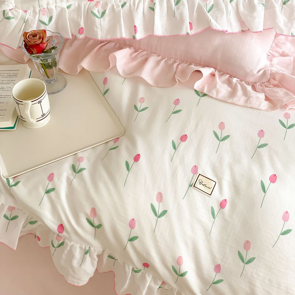 Overhead detail of the Pink Tulip Bedding Set pillow and duvet, showing the ruffle trim and a pink rose in a glass.