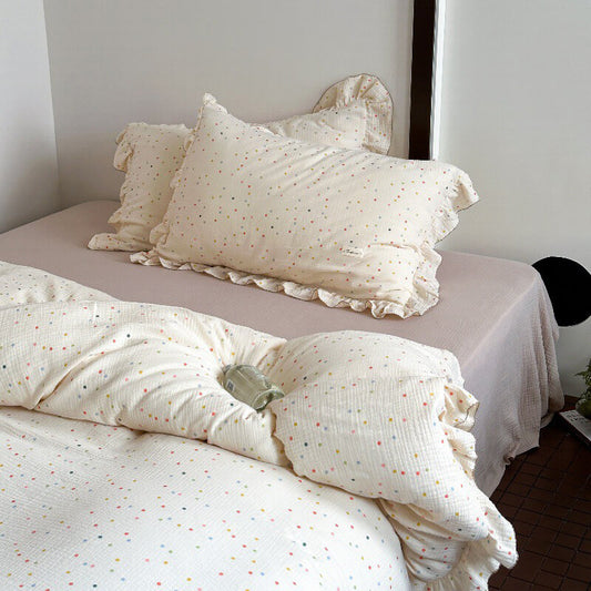 Polka dot bedding set featuring a ruffle duvet cover and shams on a bed with a mauve fitted sheet.