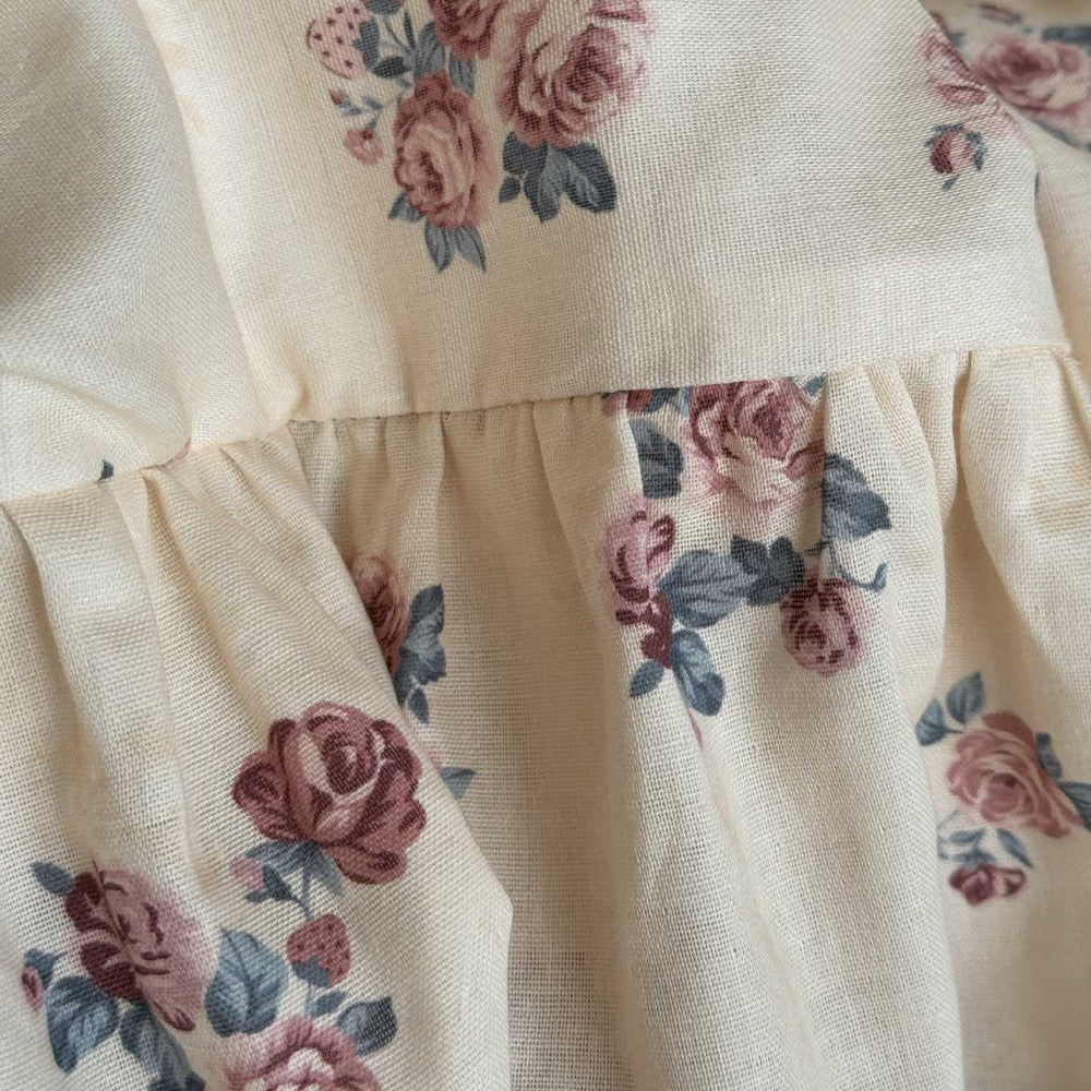 Macro shot of the ruffled cotton fabric, clearly showing the texture and the detailed print of the vintage rose floral pattern.