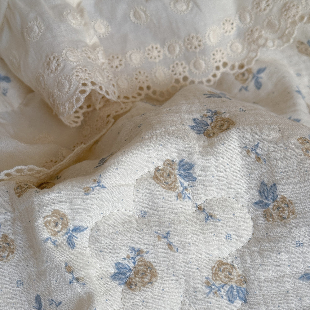 Close-up of ruffled cotton comforter with rose floral print and eyelet trim