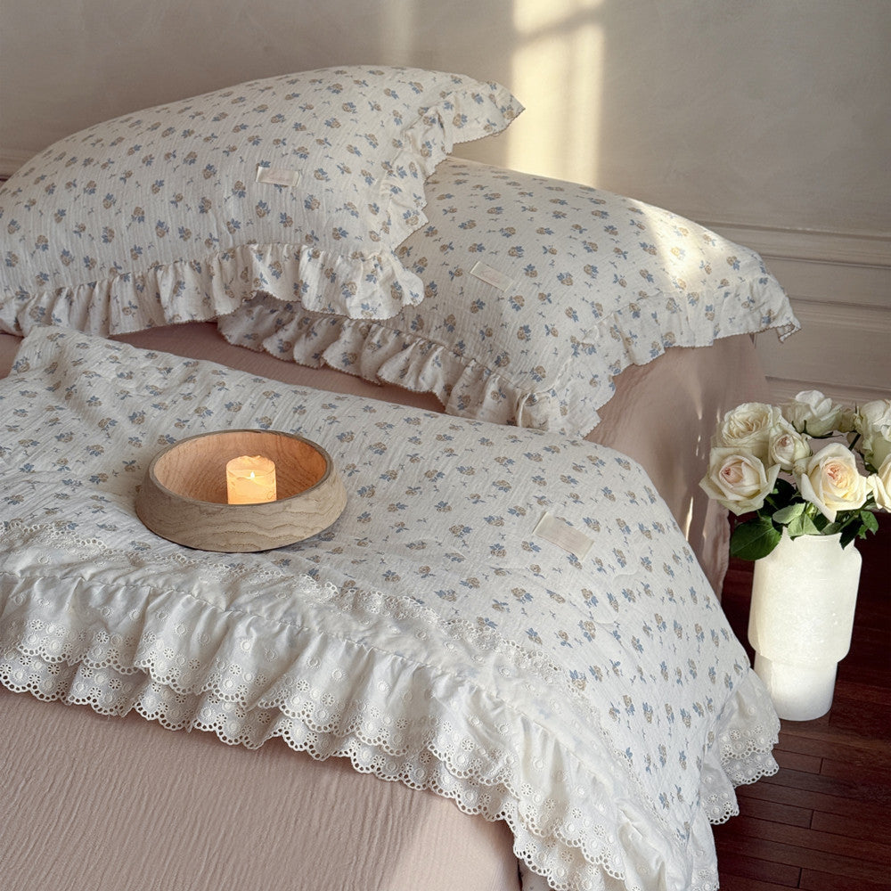 Ruffled cotton comforter styled on bed with vintage rose print