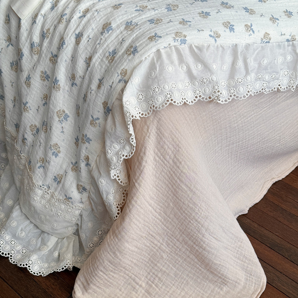 Side view of rose floral cotton gauze comforter with double ruffles and blush pink sheet