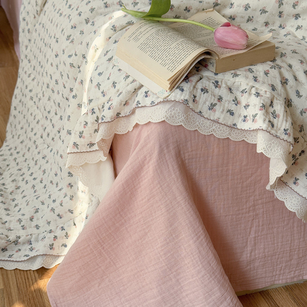 Corner view of comforter with ruffled lace over pink sheet