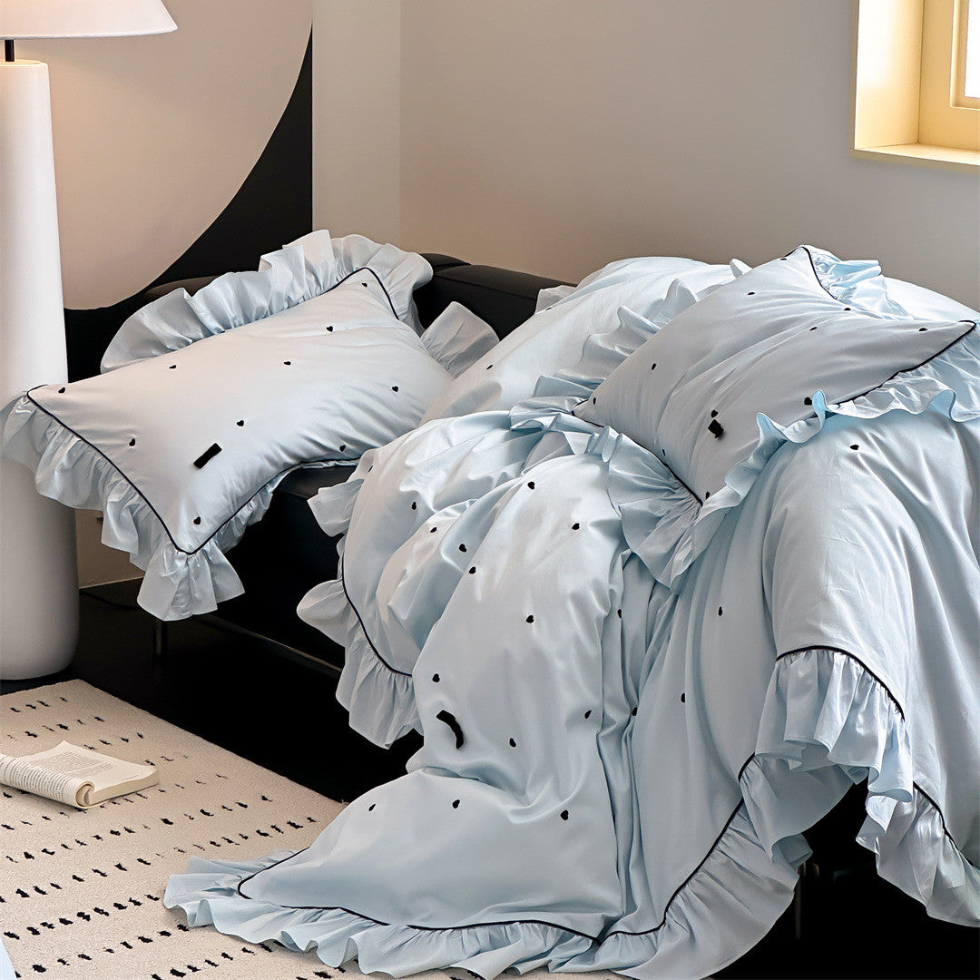 Side view of blue ruffled bedding and pillowcases with black piping