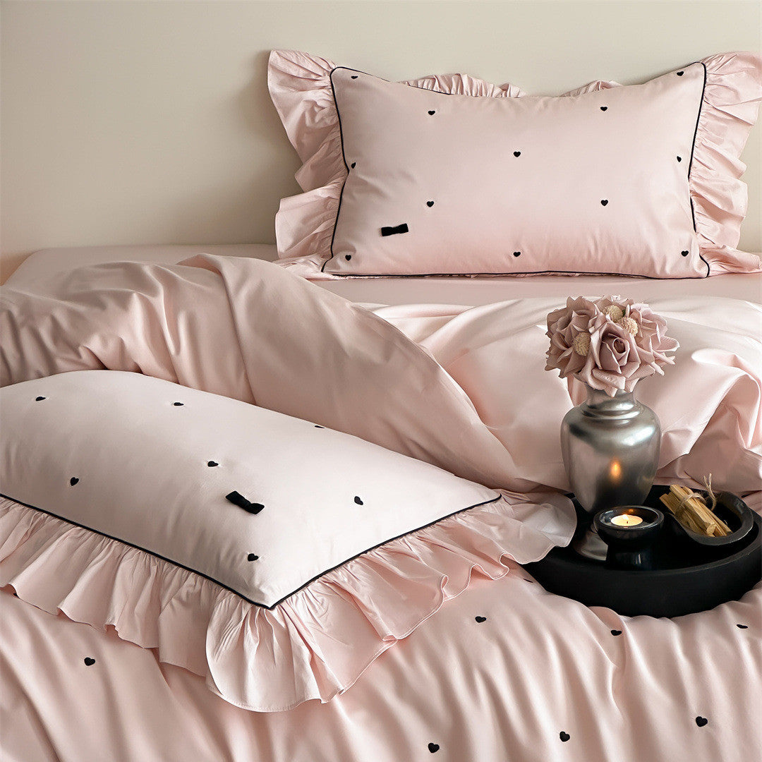 Close-up of pink duvet cover with heart embroidery and ruffle trim