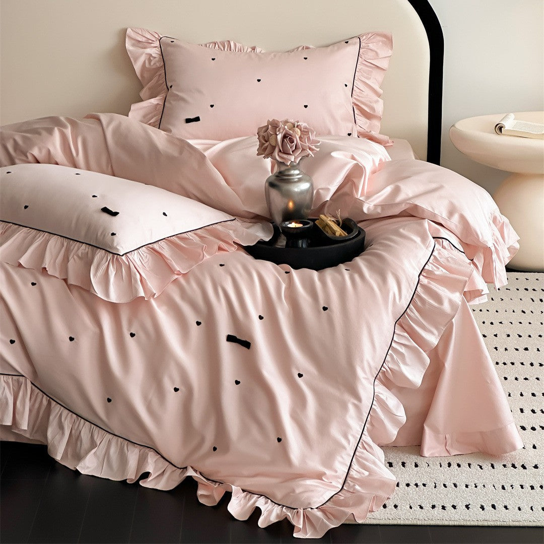 Main view of pink ruffled bedding set with black embroidered hearts