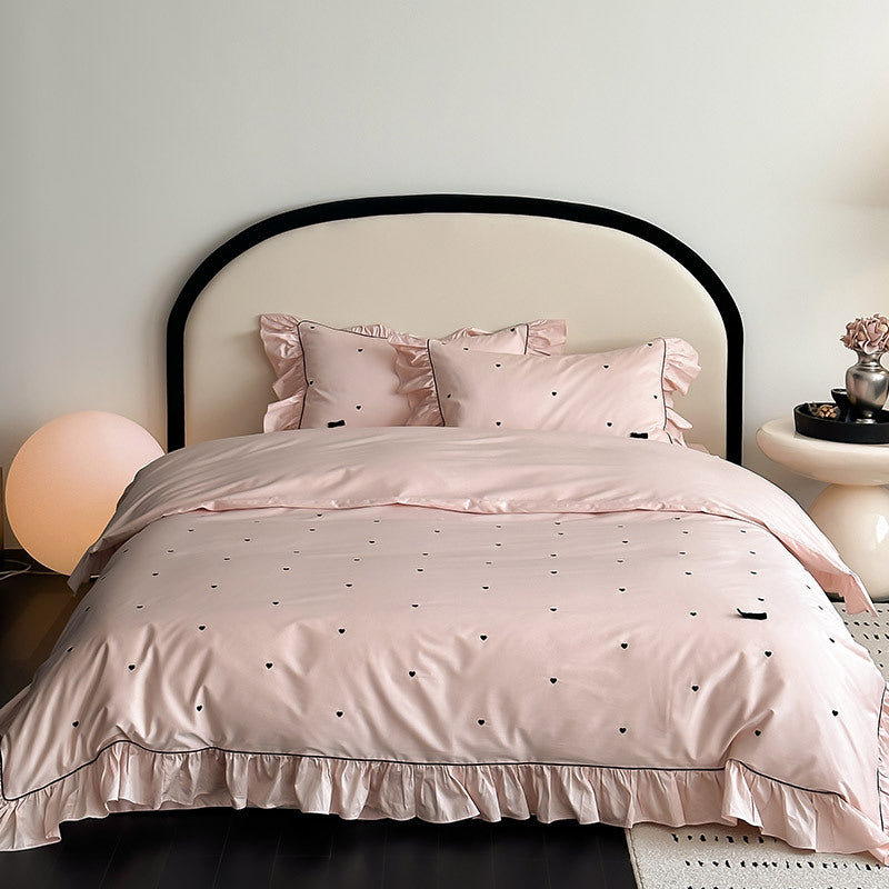 Pink pillowcase with ruffle trim and black heart embroidery