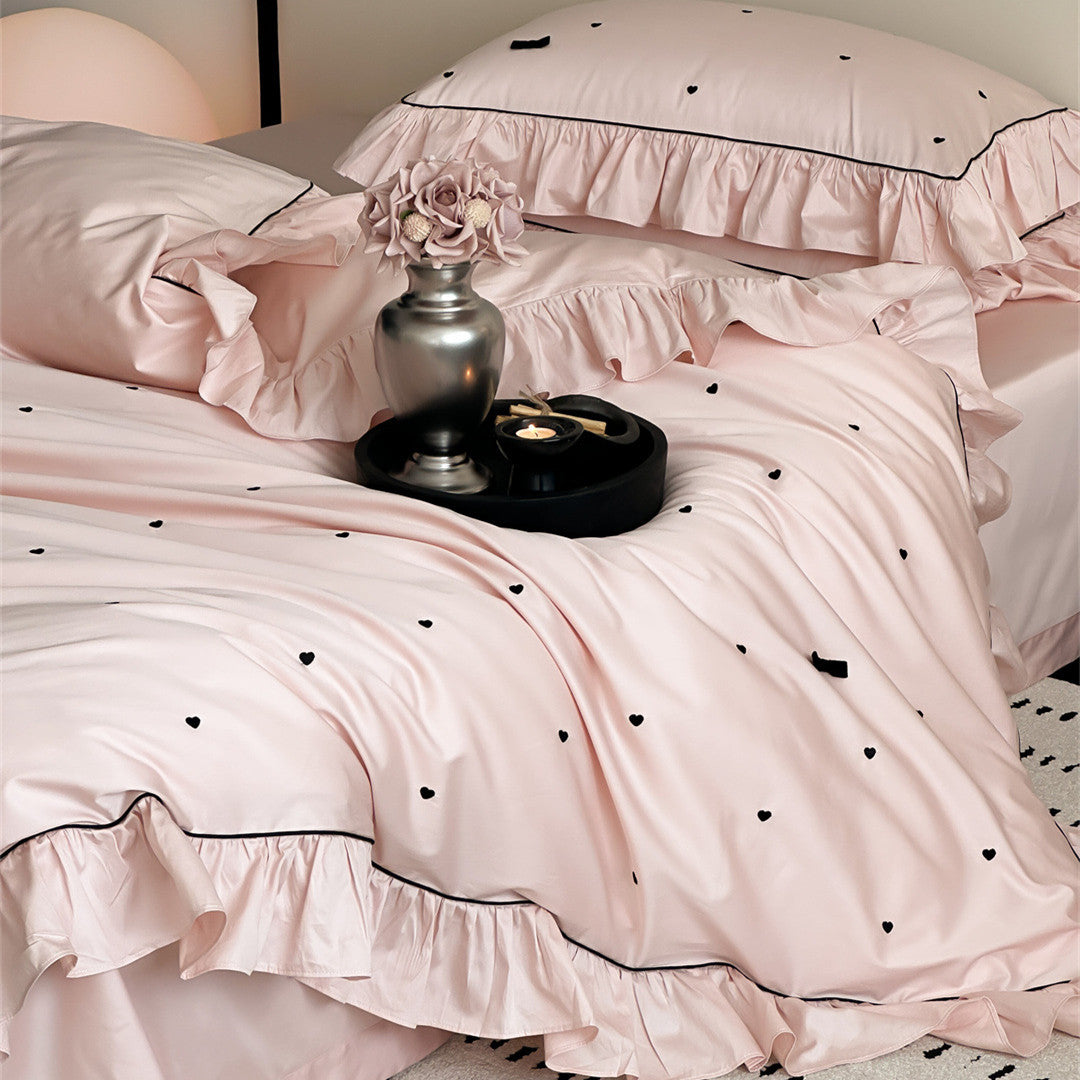 Side view of pink bedding set showing ruffles and embroidery detail