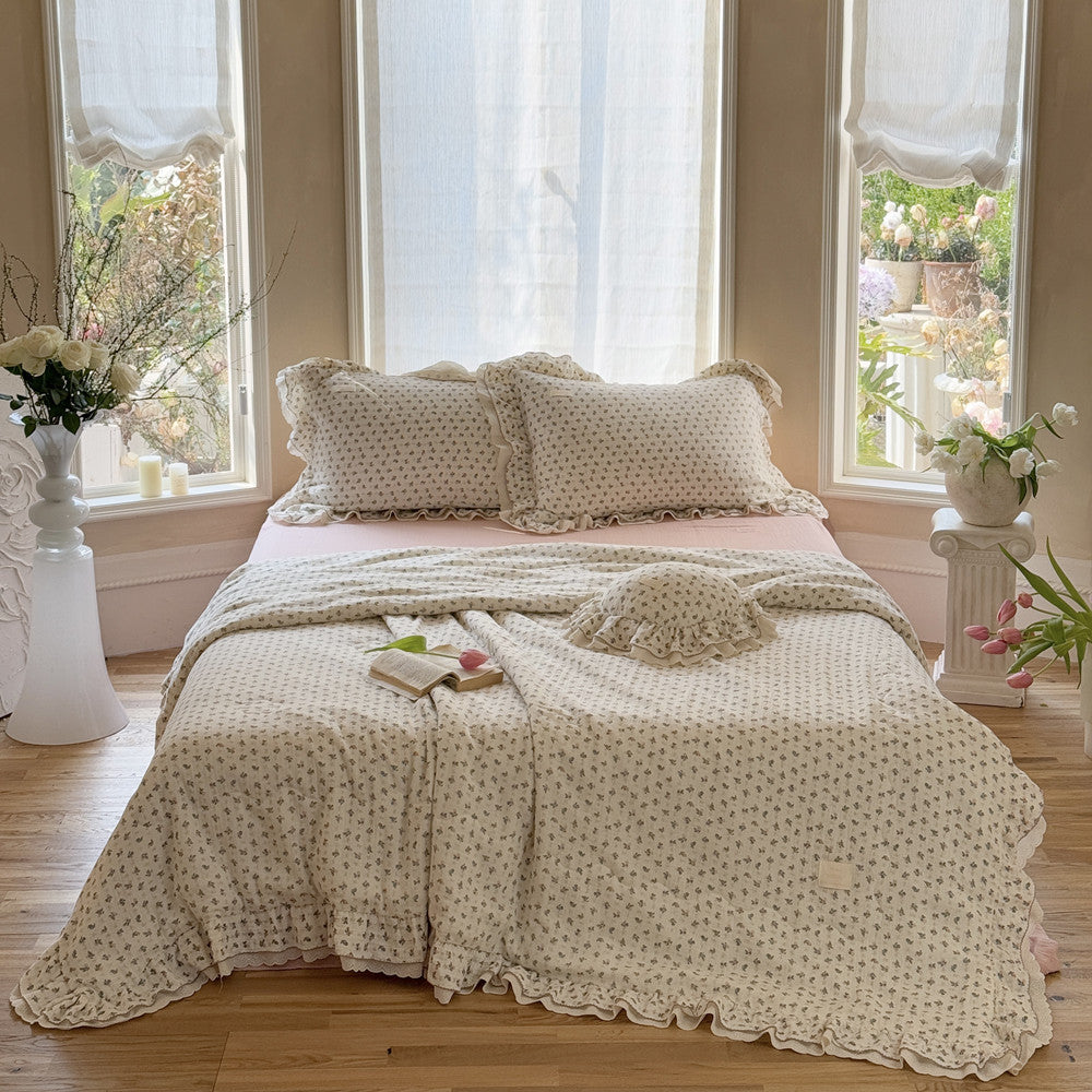 Ruffled cotton comforter with pink rosebud floral design on bed