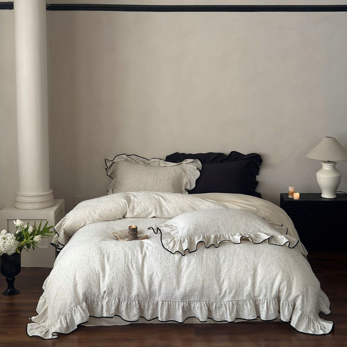 Full view of a stylish bedroom with a chic ruffled cotton bedding set, featuring a white textured duvet with black trim, and an accent black pillow.