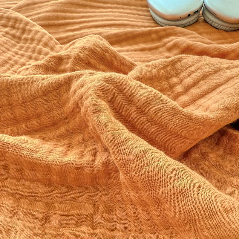 Detailed close-up showing the soft, breathable texture of the terracotta 6-layer cotton gauze blanket.