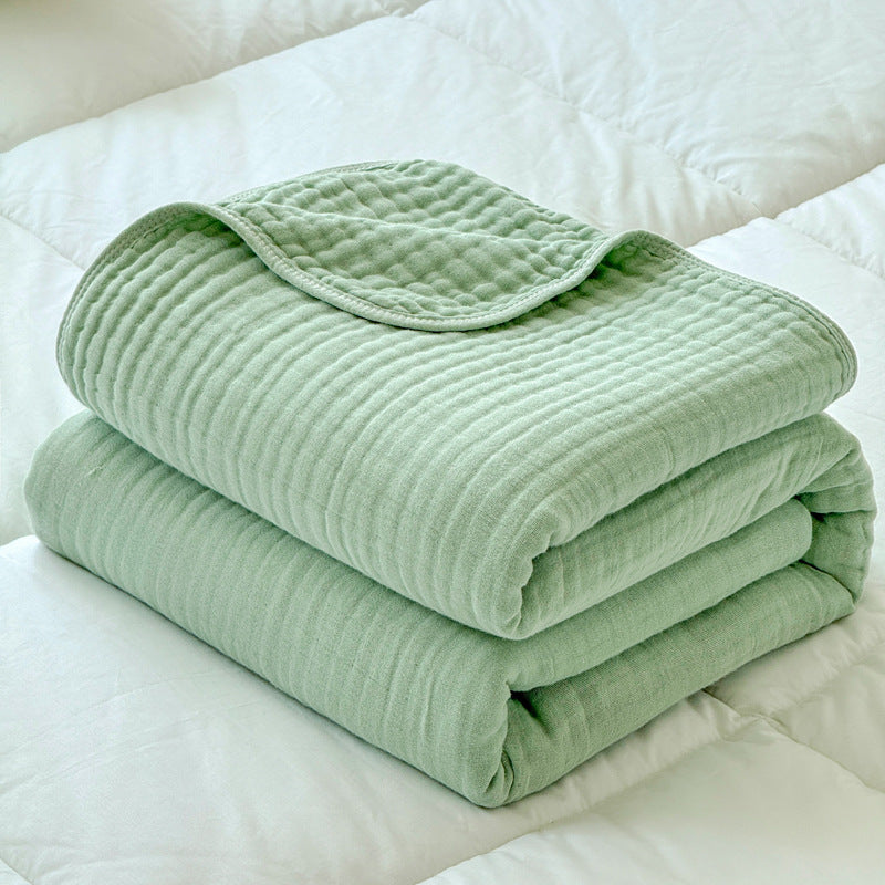 A neatly folded sage green 6-layer cotton gauze blanket, showing its thickness and soft, layered texture.