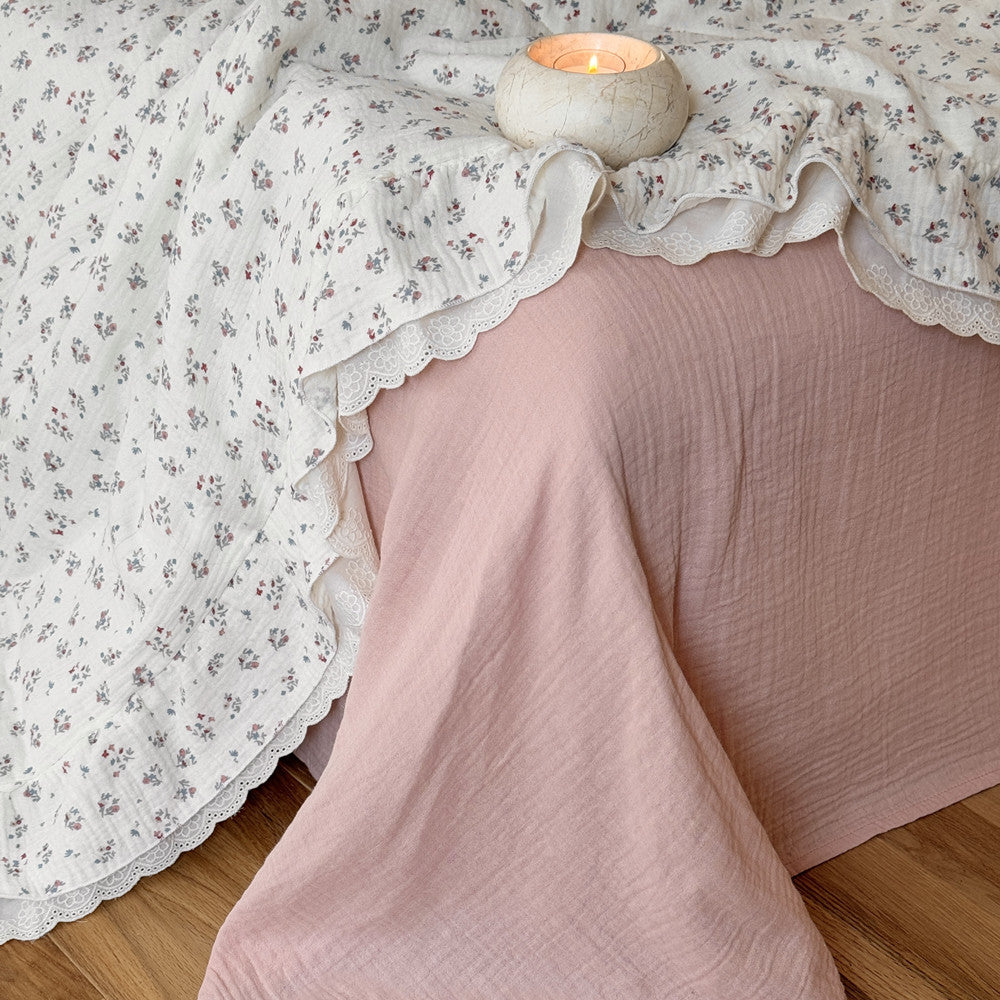 Dusty pink bed sheet paired with a lightweight floral comforter and romantic lace trim