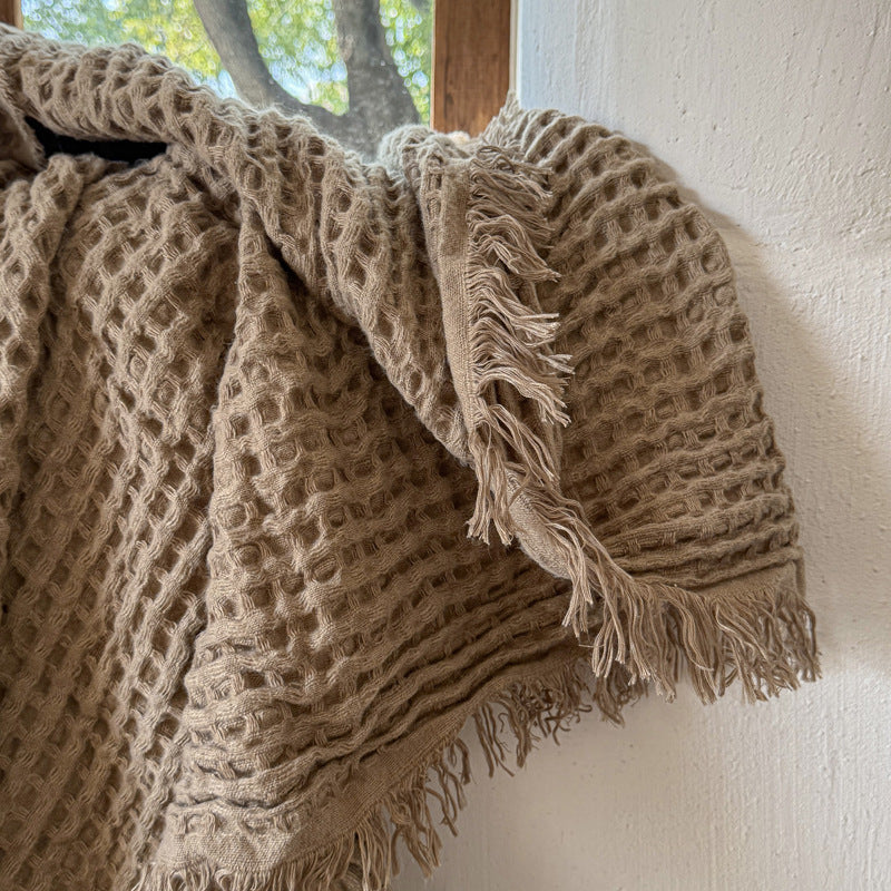 Close-up of textured brown waffle weave throw with fringe
