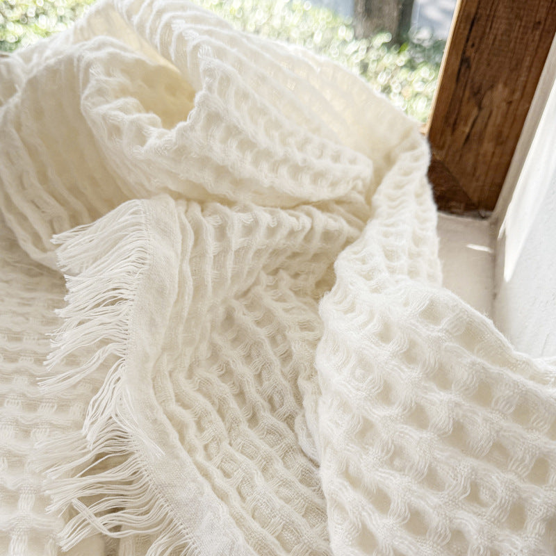 Textured detail of white waffle weave throw with fringe