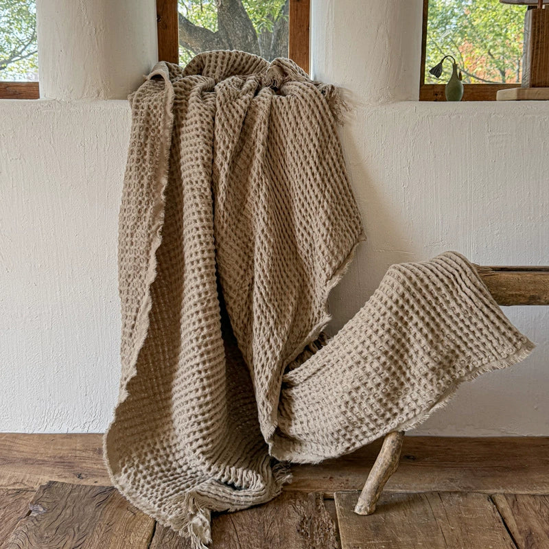 Brown waffle weave fringle throw draped over rustic bench