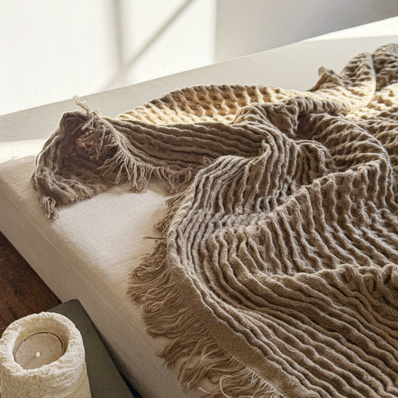 Relaxed waffle weave throw blanket in brown on soft surface
