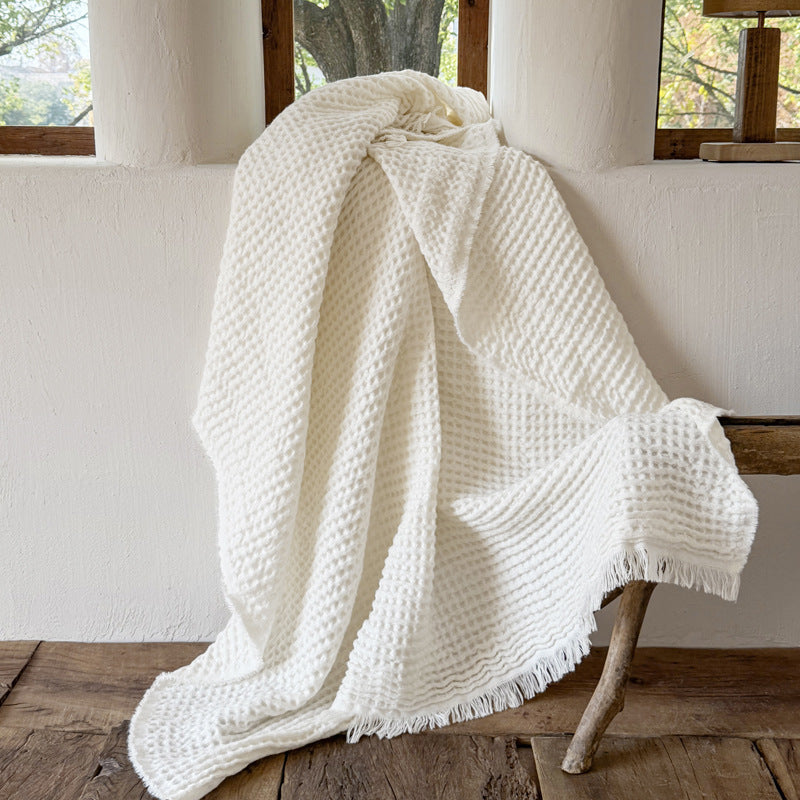 Cream waffle weave throw blanket hanging in natural light