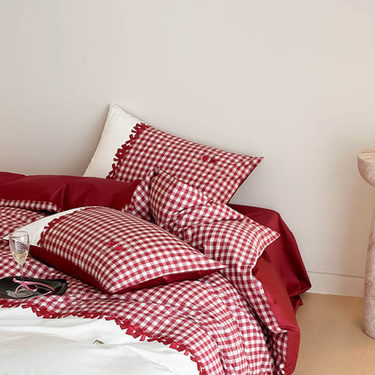 Red and white gingham cotton bedding set with pillows and comforter on light beige floor and wall