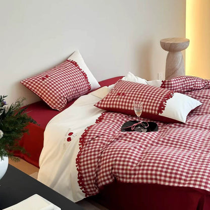 Red and white 100s gingham cotton bedding set with embroidered cherries on a neatly made bed