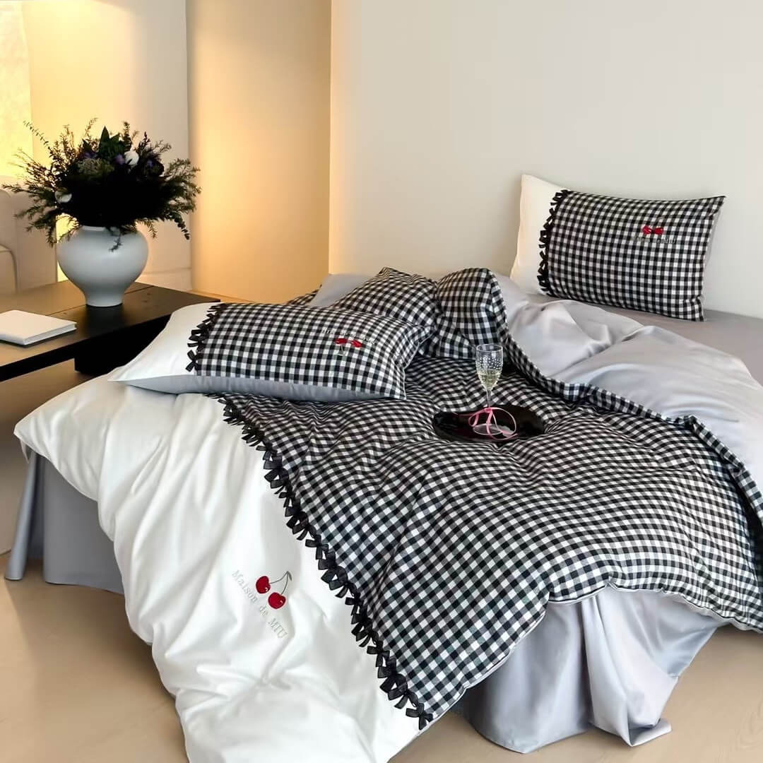 Black and white gingham cotton bedding set with decorative ruffled edges and cherry embroidery on bed in minimal bedroom