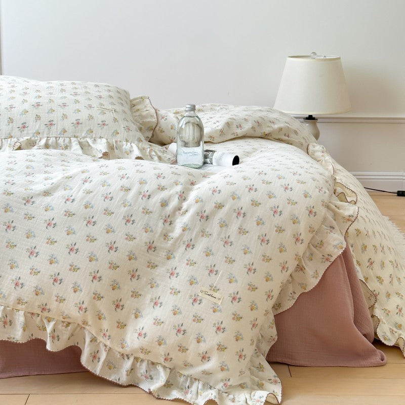Floral patterned bedspread on a bed with a lamp and water bottle in the background.