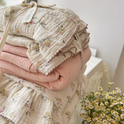 Stack of folded baby blankets with floral patterns on a white surface.