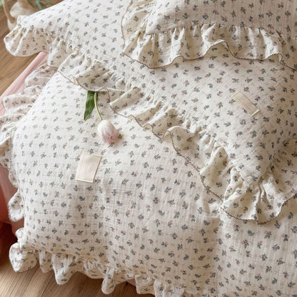 Extreme close-up of a ruffled pillow sham from the Bellflower Floral Cotton Gauze Set, showing the delicate ditsy print and the contrasting pink stitched ruffle detail