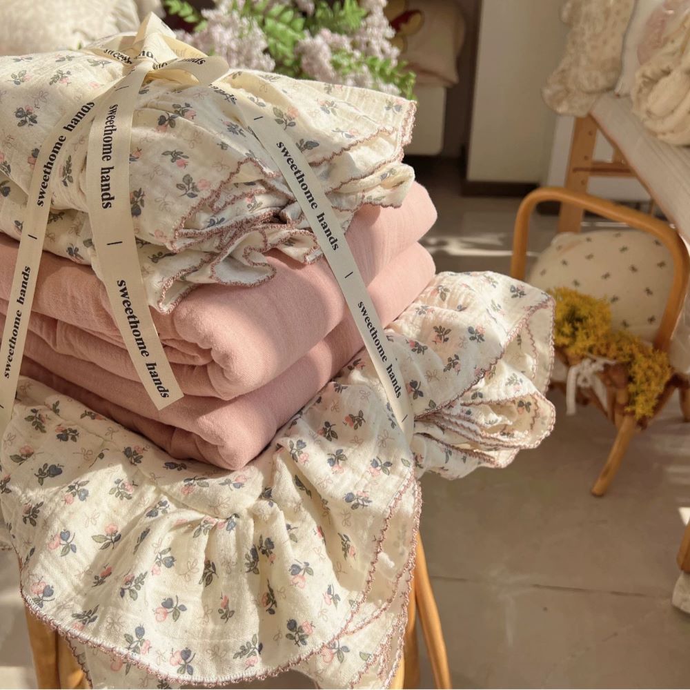 Folded Bellflower Floral Cotton Gauze Bedding Set tied with a ribbon, showcasing the floral pattern and a coordinating solid pink cotton sheet, presented as a premium, gift-ready bedding package.