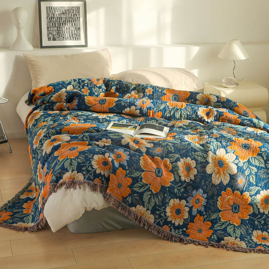 Blue daisy floral cotton throw blanket with fringe styled on a white bed