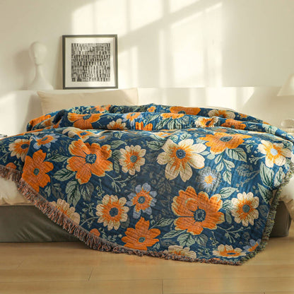 Blue and orange daisy floral cotton throw blanket layered across a bed