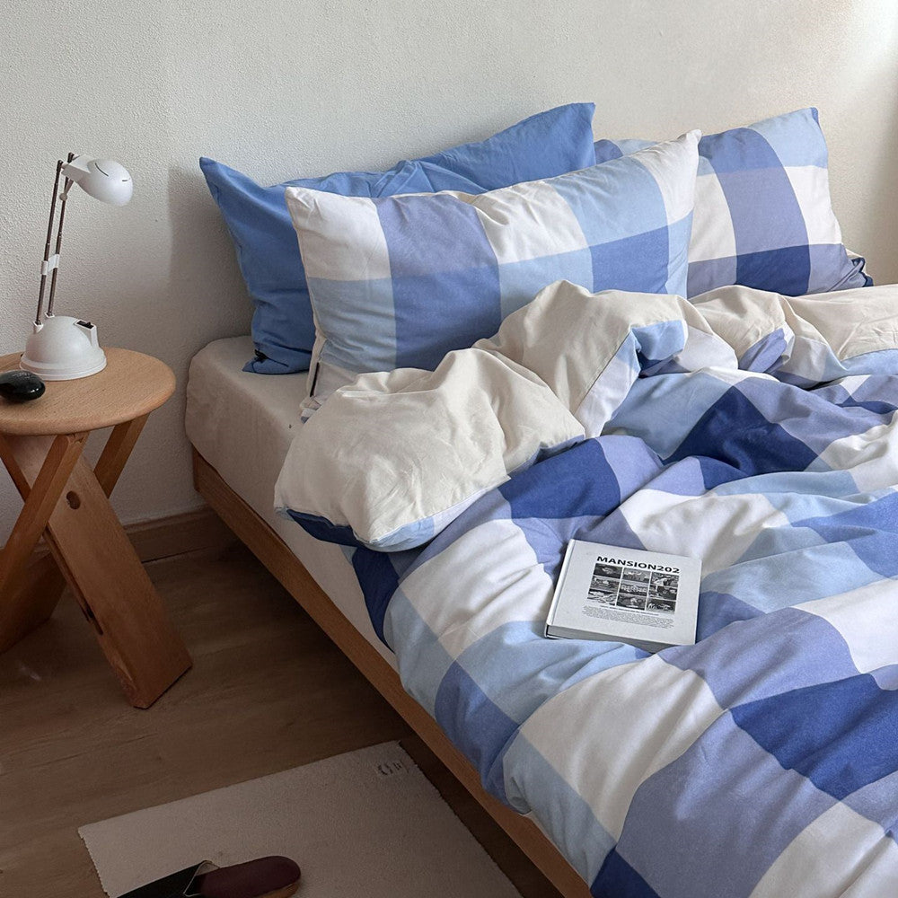 Blue plaid cotton bedding set with pillows on wooden bed in cozy bedroom