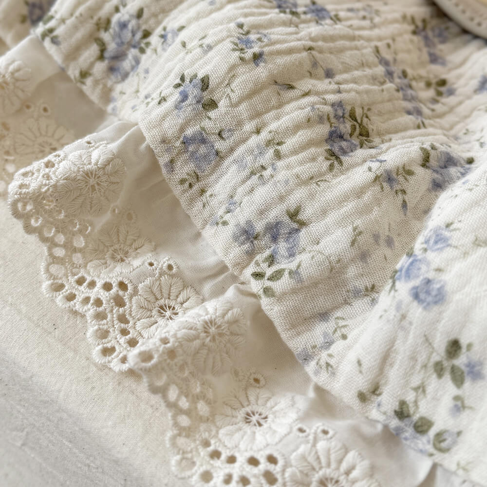 Macro detail of blue rose muslin fabric with white embroidered ruffled lace trim