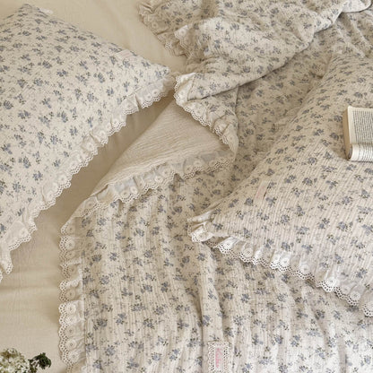 Blue rose cotton comforter styled in a relaxed cottage bedroom with open book detail