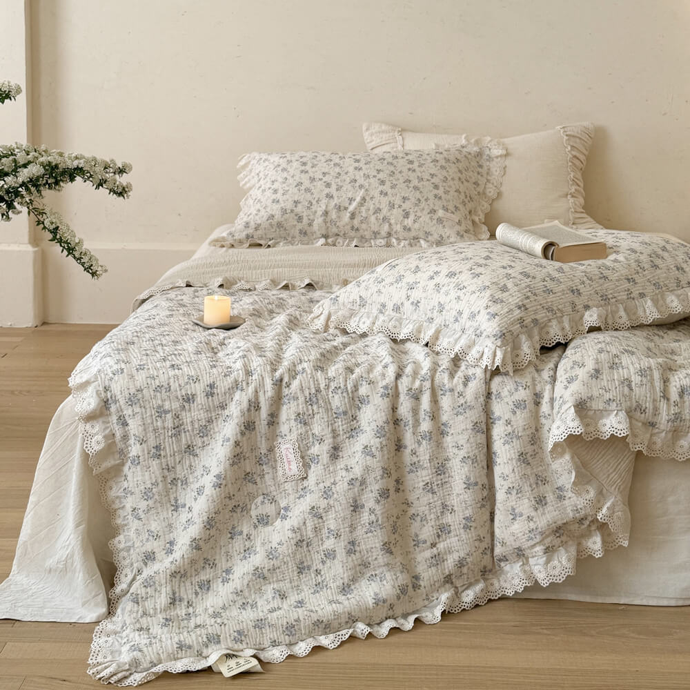 Blue rose cotton comforter styled in a relaxed cottage bedroom with open book detail