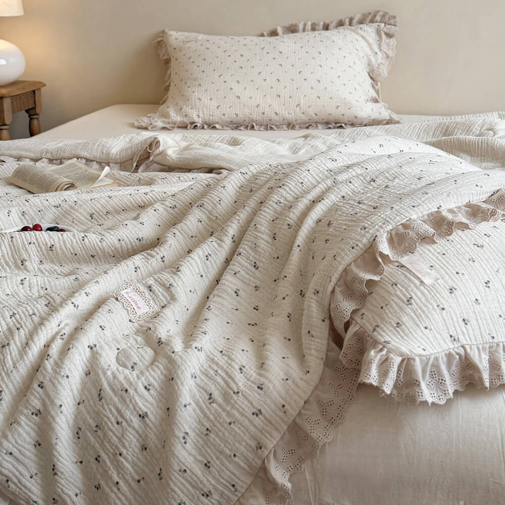 Breathable crinkled cotton gauze summer blanket with a tiny blueberry and leaf print, showcasing elegant eyelet lace ruffled edges on a vintage cottage style bed.