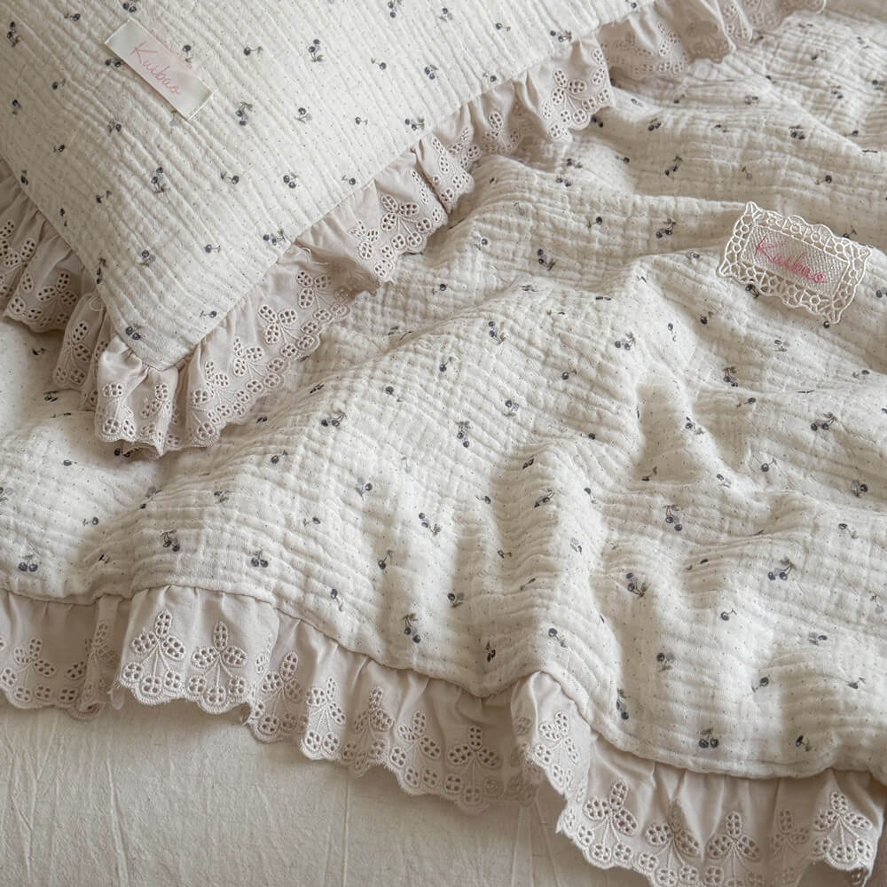 Macro shot of soft, organic crinkled muslin fabric with detailed eyelet ruffle lace trimming, emphasizing the high-quality textures of the romantic blueberry print bedding.