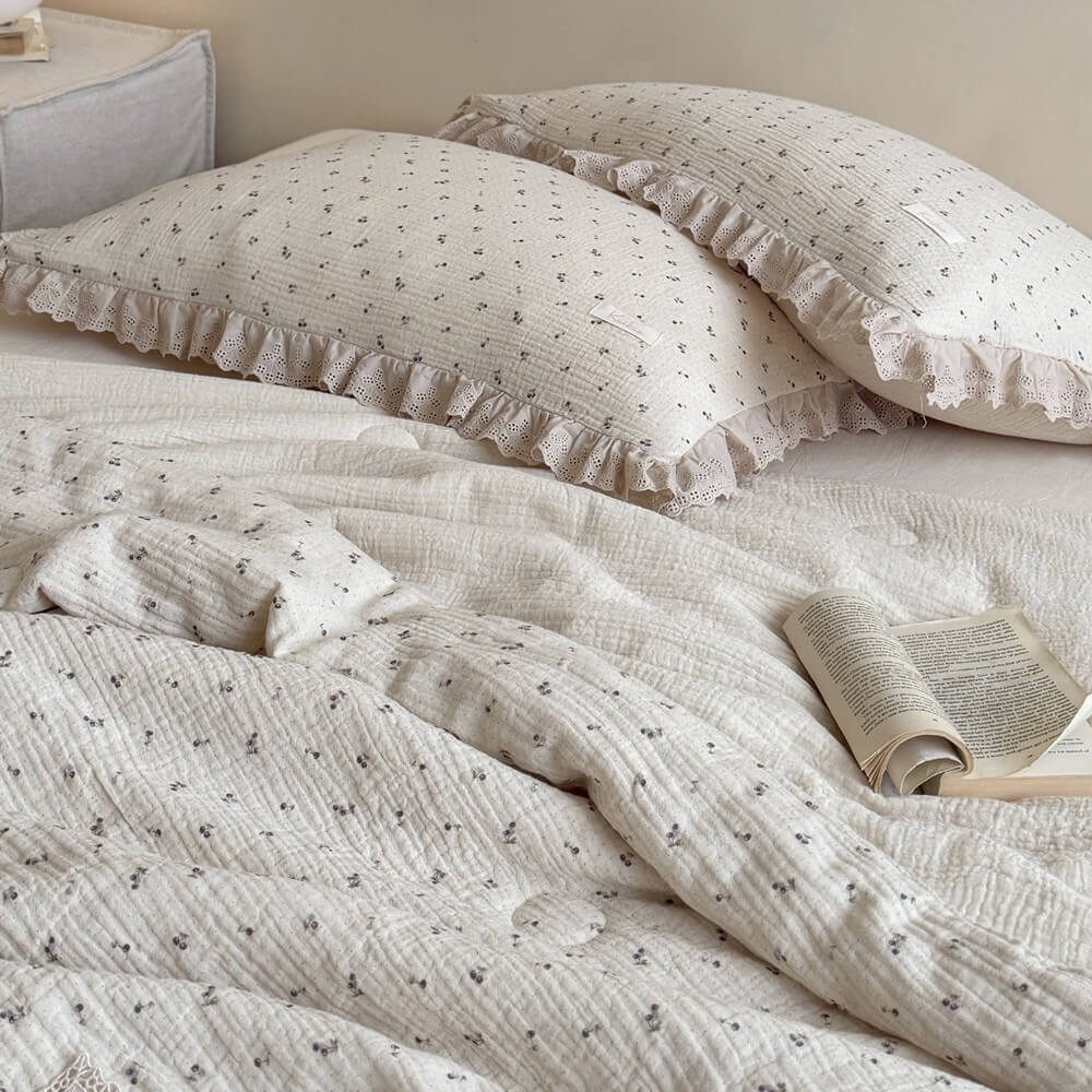 A pair of vintage aesthetic blueberry pattern ruffled pillowcases with lace borders, layered on a cream-colored bed with an open book for a dreamy aesthetic.