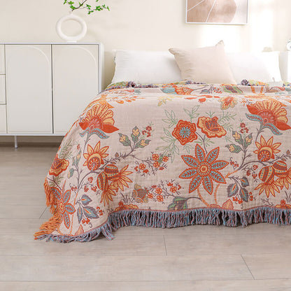 Side view of a vintage-style floral jacquard coverlet with tassel fringe draping over a bed, highlighting the large-scale botanical print.