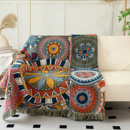 Boho geometric cotton throw blanket with fringe draped over a sofa