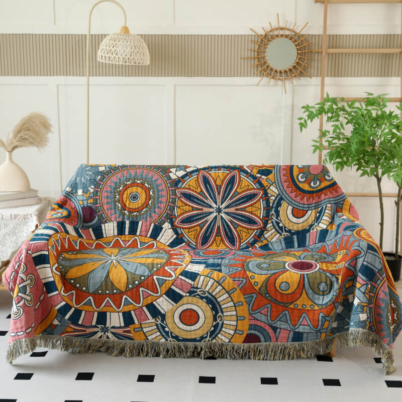 Boho geometric cotton throw blanket with fringe layered over a cream sofa