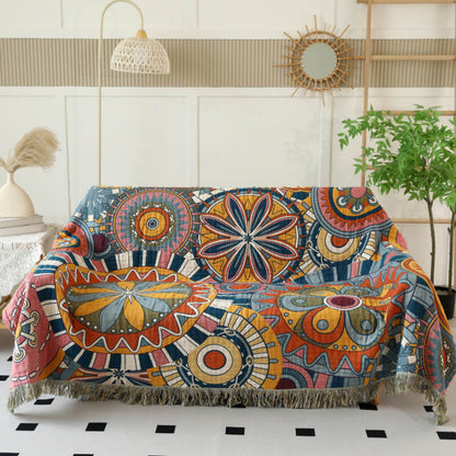 Boho geometric cotton throw blanket with fringe layered over a cream sofa