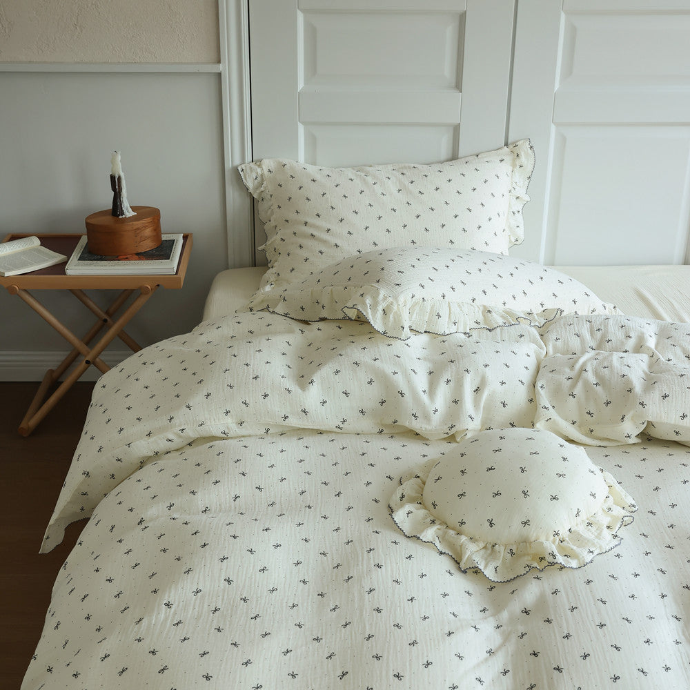 Bow print ruffled bedding set displayed on a queen bed, including the duvet cover and two pillows, emphasizing the sweet, vintage aesthetic.