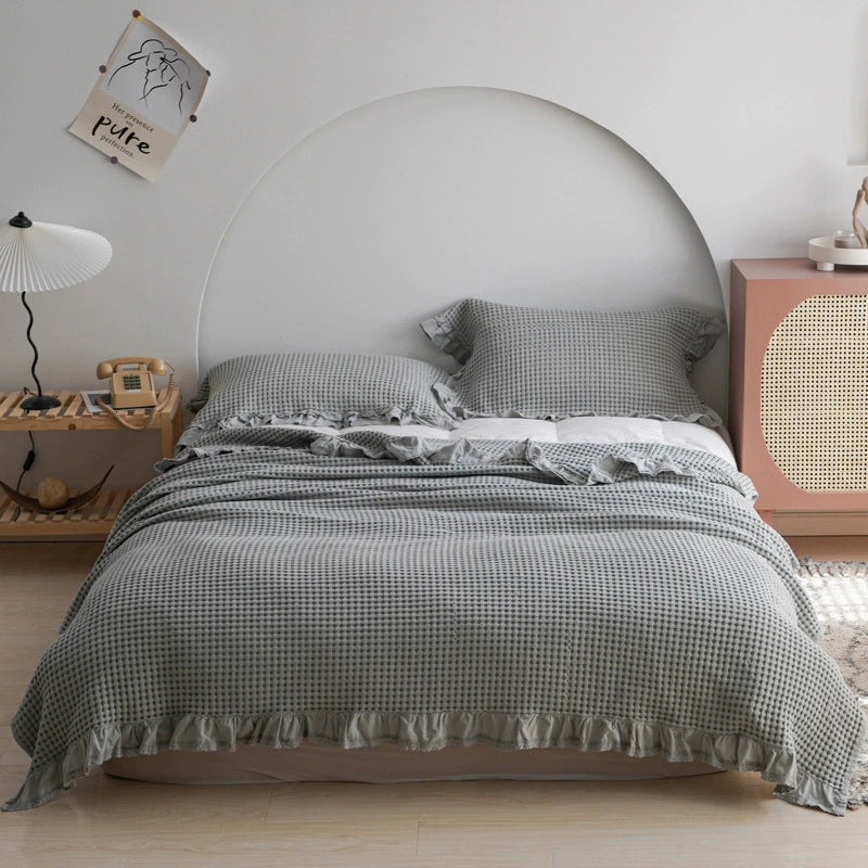 Grey waffle weave blanket set with matching ruffled pillowcases for a cozy bedroom look.